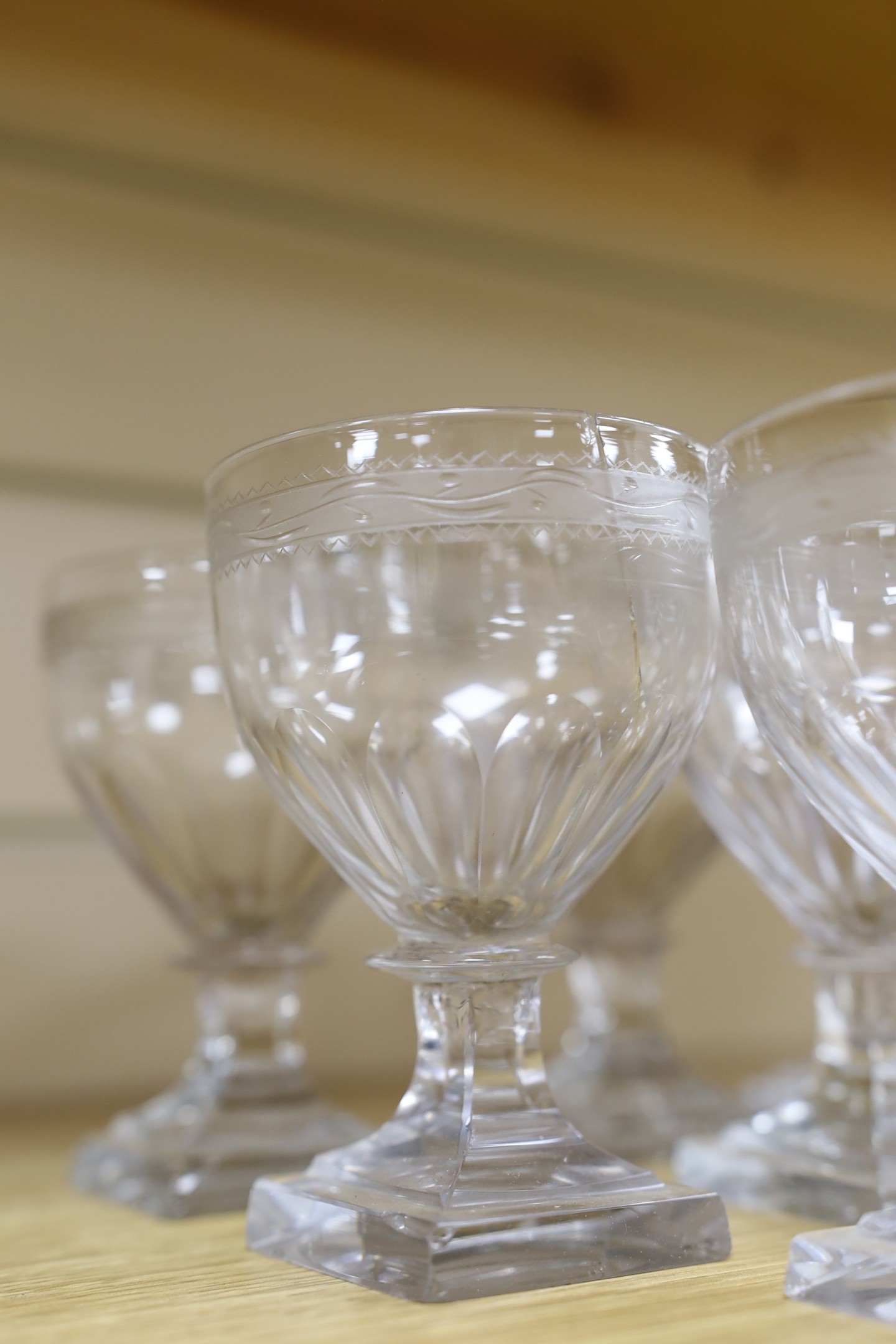 A set of eleven early 19th century engraved wine glasses, square foot, 11cm tall